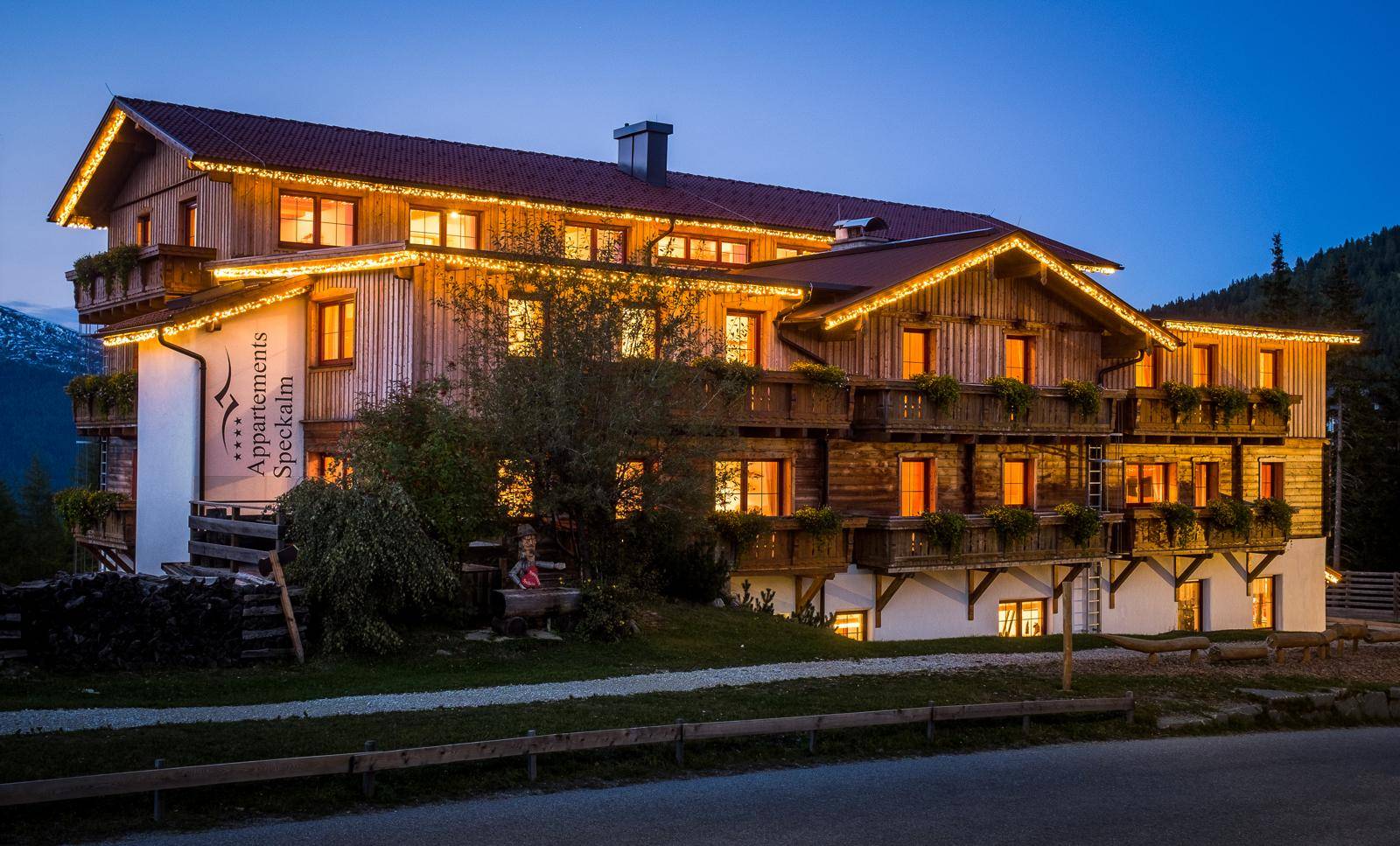 Beleuchtetes Holzgebäude in der Abenddämmerung mit festlicher Dekoration und Balkonen.