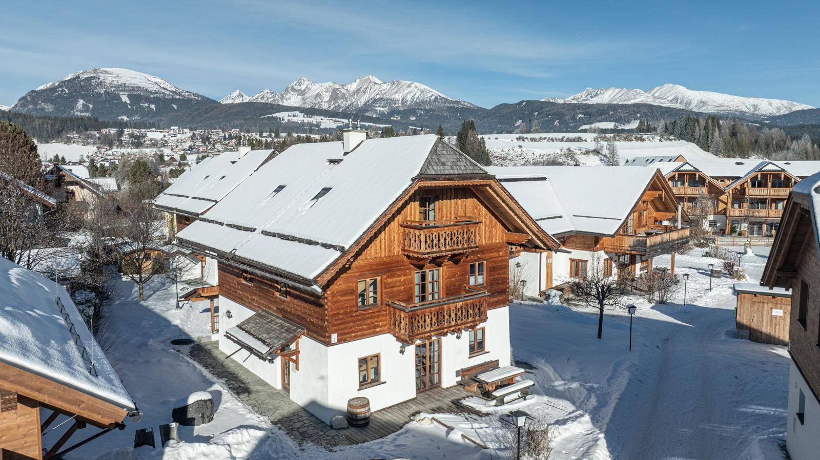 Charmantes Chalet mit Holzbalkonen und verschneitem Satteldach in einer idyllischen Winterlandschaft.