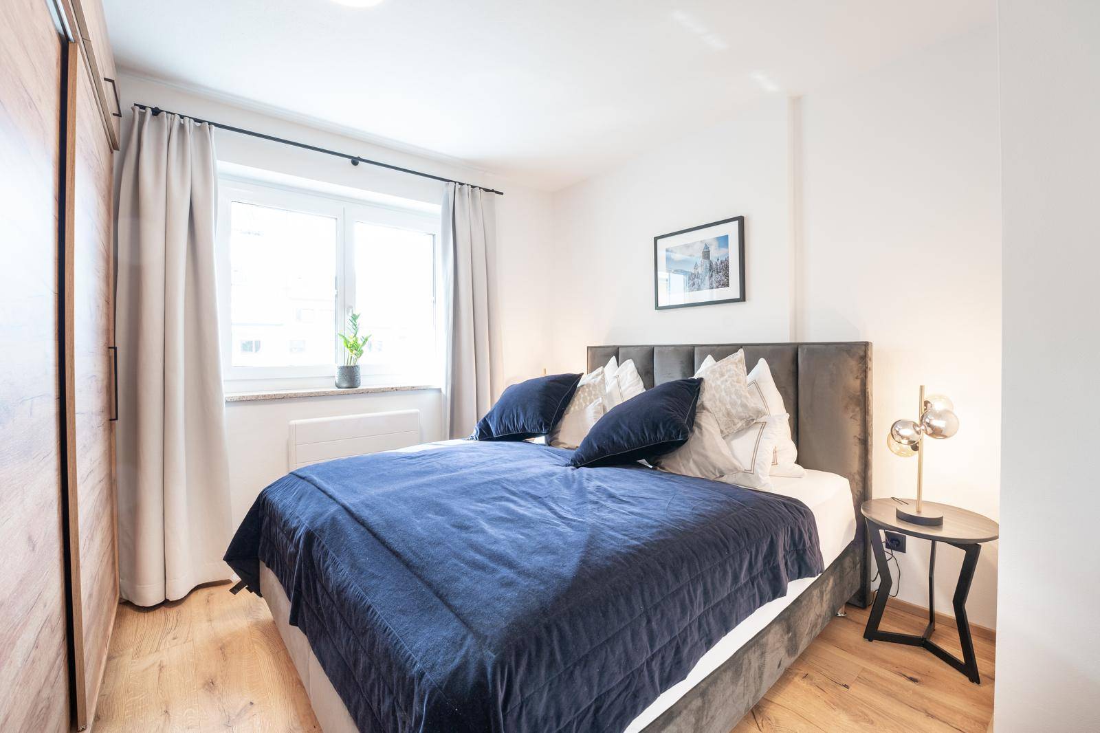 Gemütliches Schlafzimmer mit Doppelbett, Holzboden und großem Fenster.