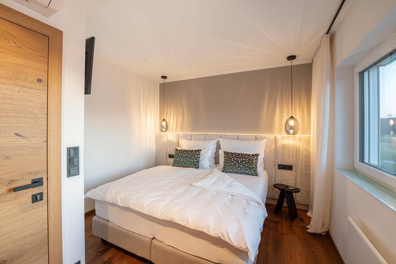 Gemütliches Schlafzimmer mit großem Bett, indirekter Beleuchtung und Holzboden.