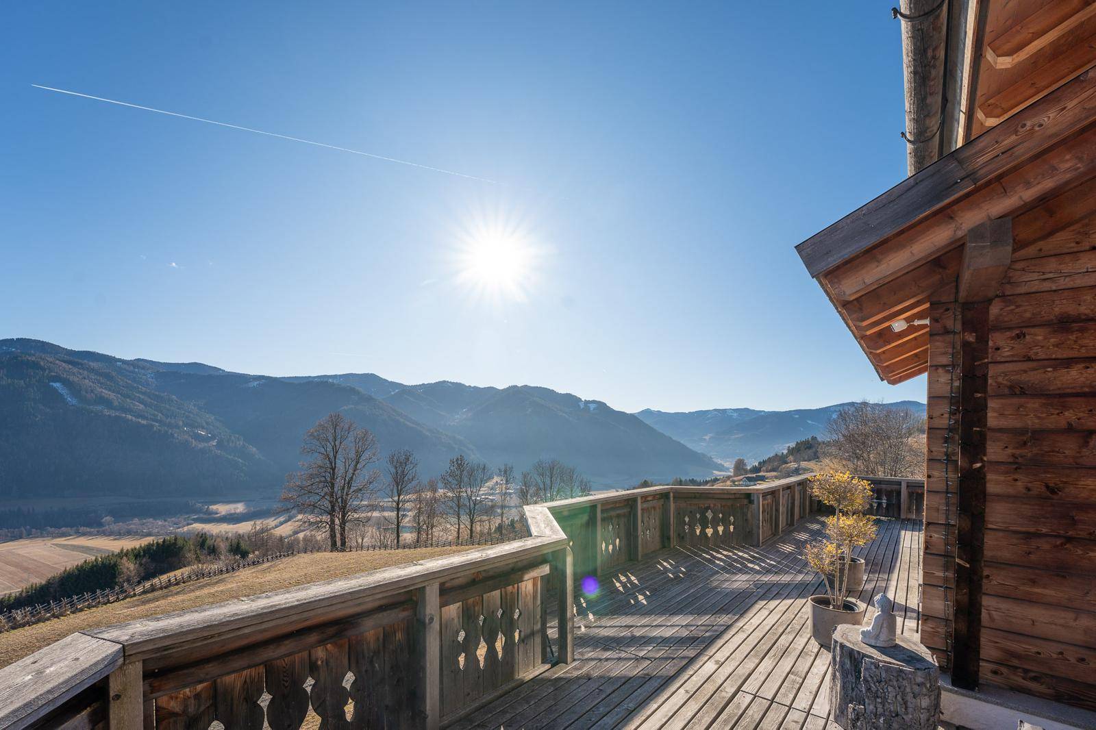 Großer Holzbalkon mit traditionellem Geländer und weitem Blick auf die Berglandschaft.