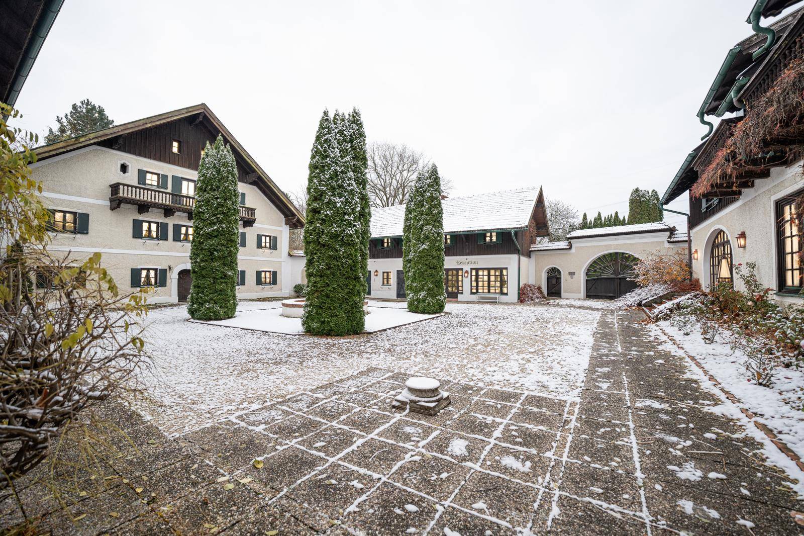 Verschneiter Innenhof mit traditionellen Gebäuden und gepflastertem Boden.