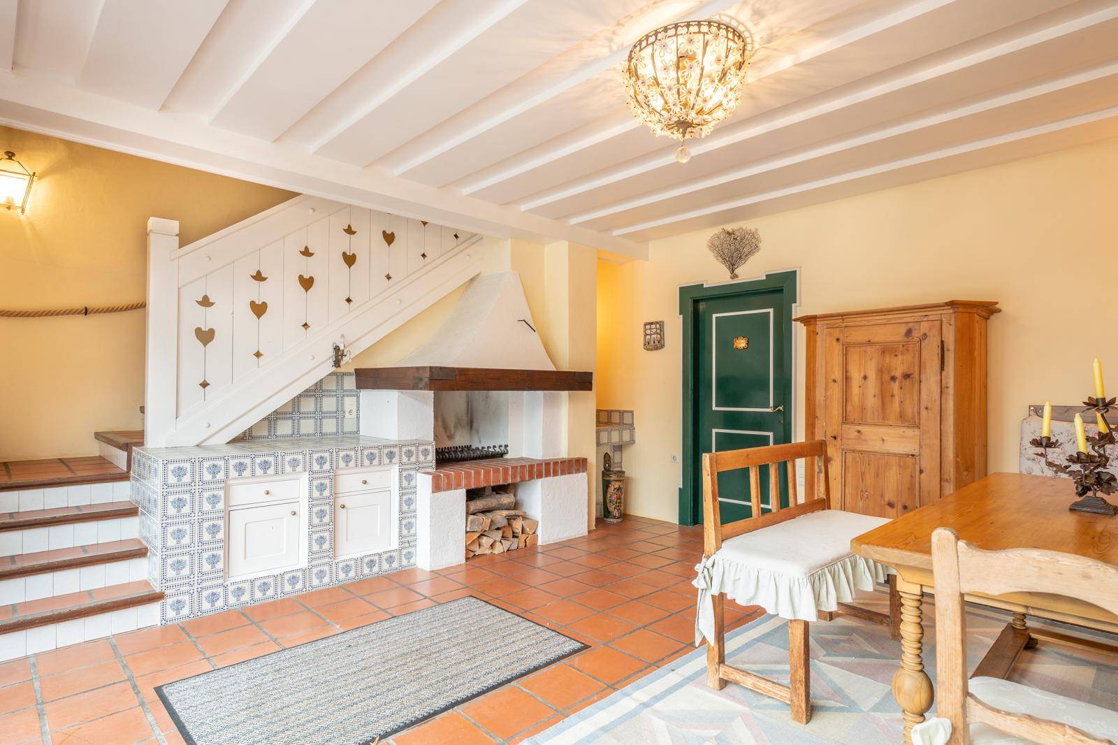 Rustikaler Wohnbereich mit offenem Kamin, Holztreppe und traditionellen Fliesen.