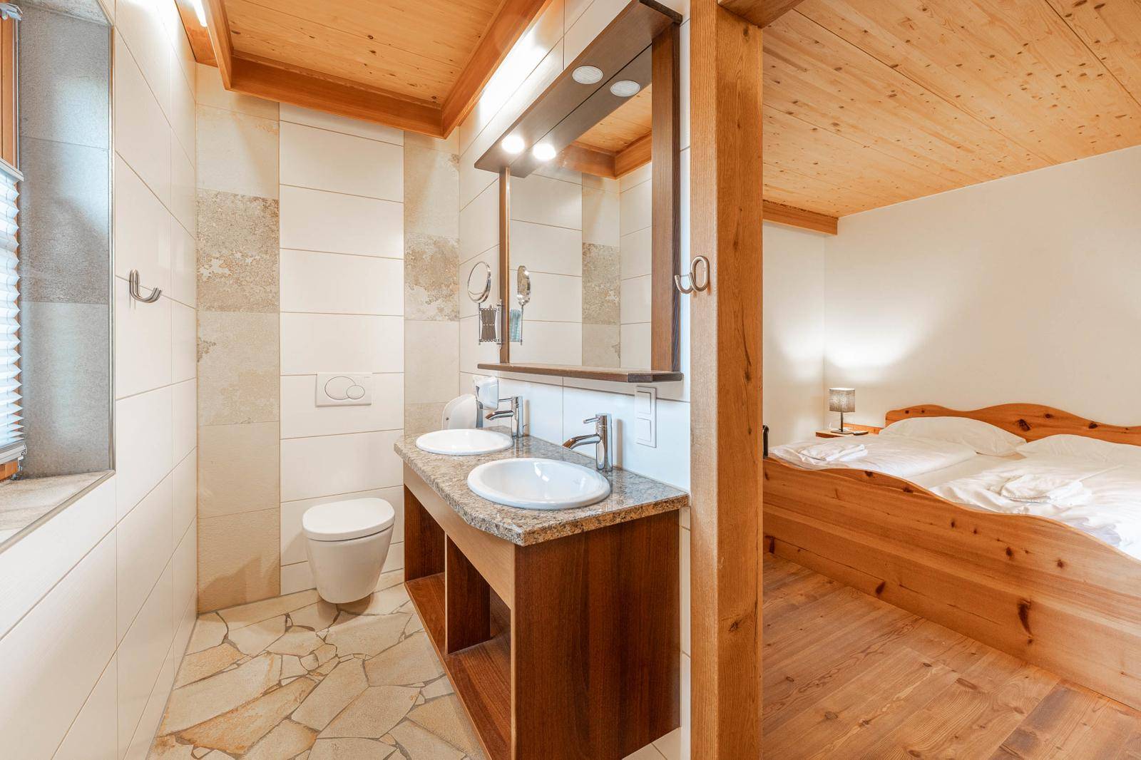 Ensuite-Badezimmer mit Doppelwaschbecken, Wand-WC und Holzbalkendecke.