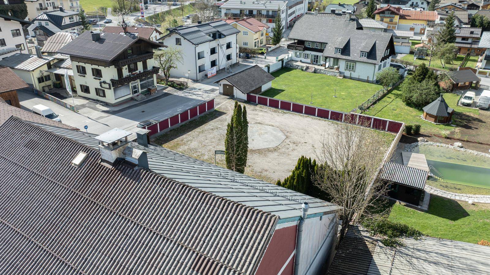 Luftaufnahme eines Grundstücks mit angrenzenden Häusern, einem leeren Feld und einem kleinen Poolbereich.