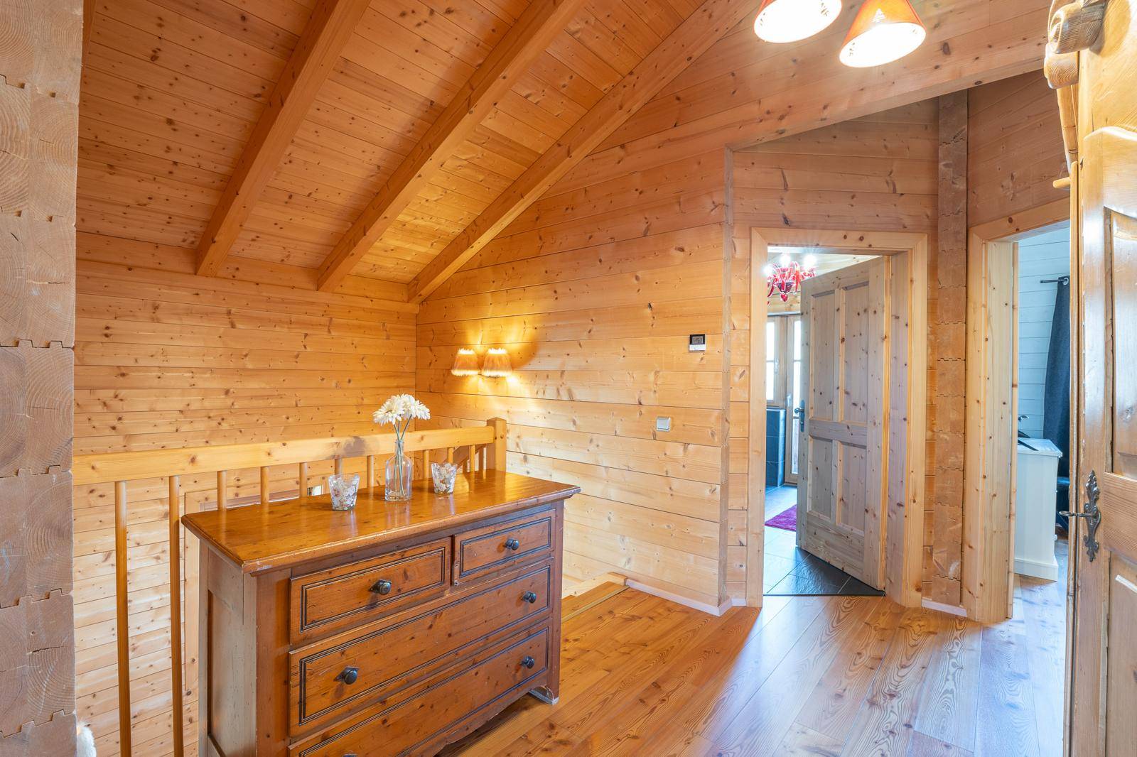 Heller Flur mit Holzwänden, Holzbalkendecke und traditioneller Holzkommode.