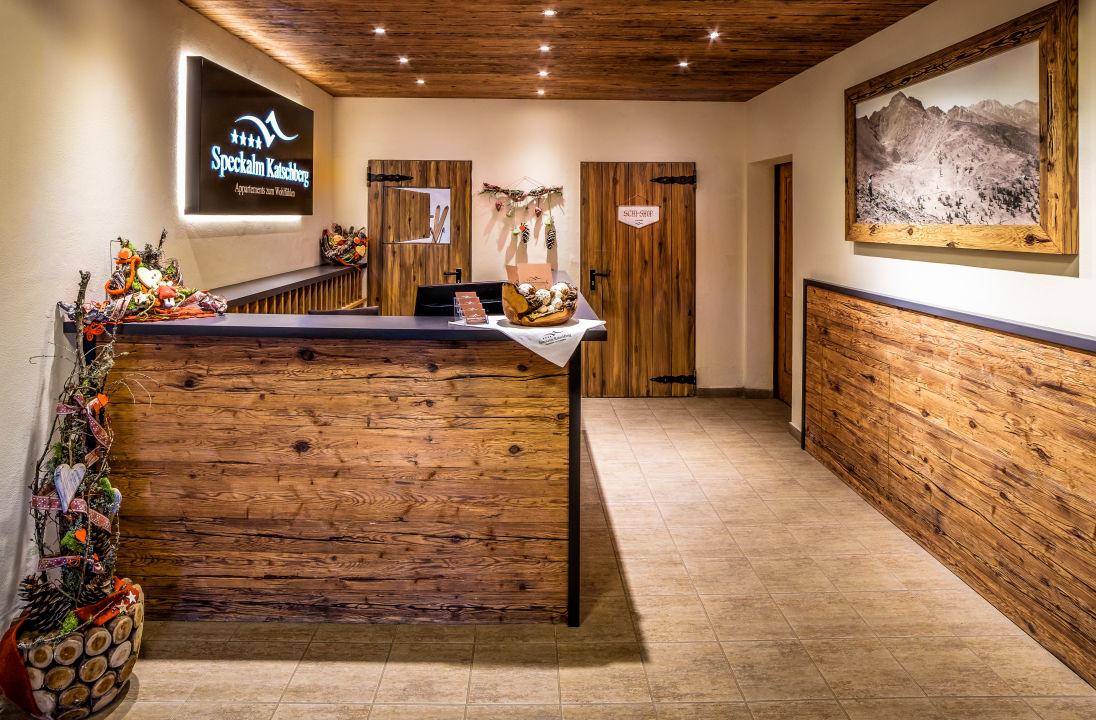 Empfangsbereich im alpinen Stil mit Holztheke, Fliesenboden und rustikalen Türen.