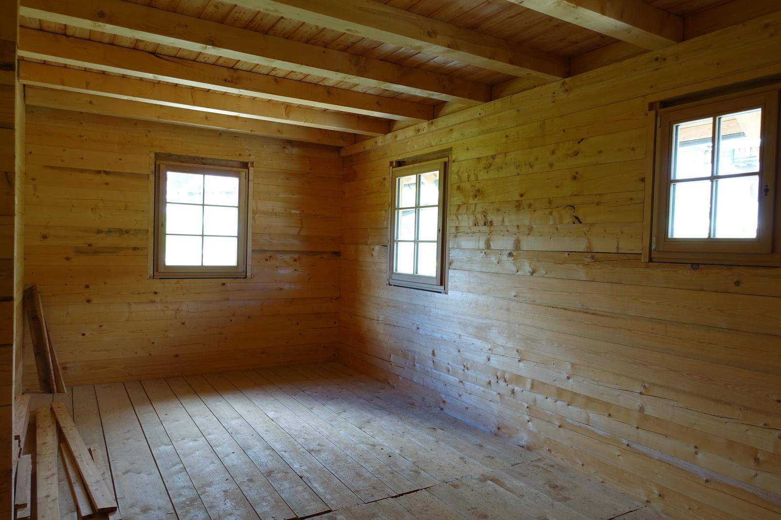 Heller Raum mit Holzwänden, Holzboden und Fenstern, die viel Licht hereinlassen.