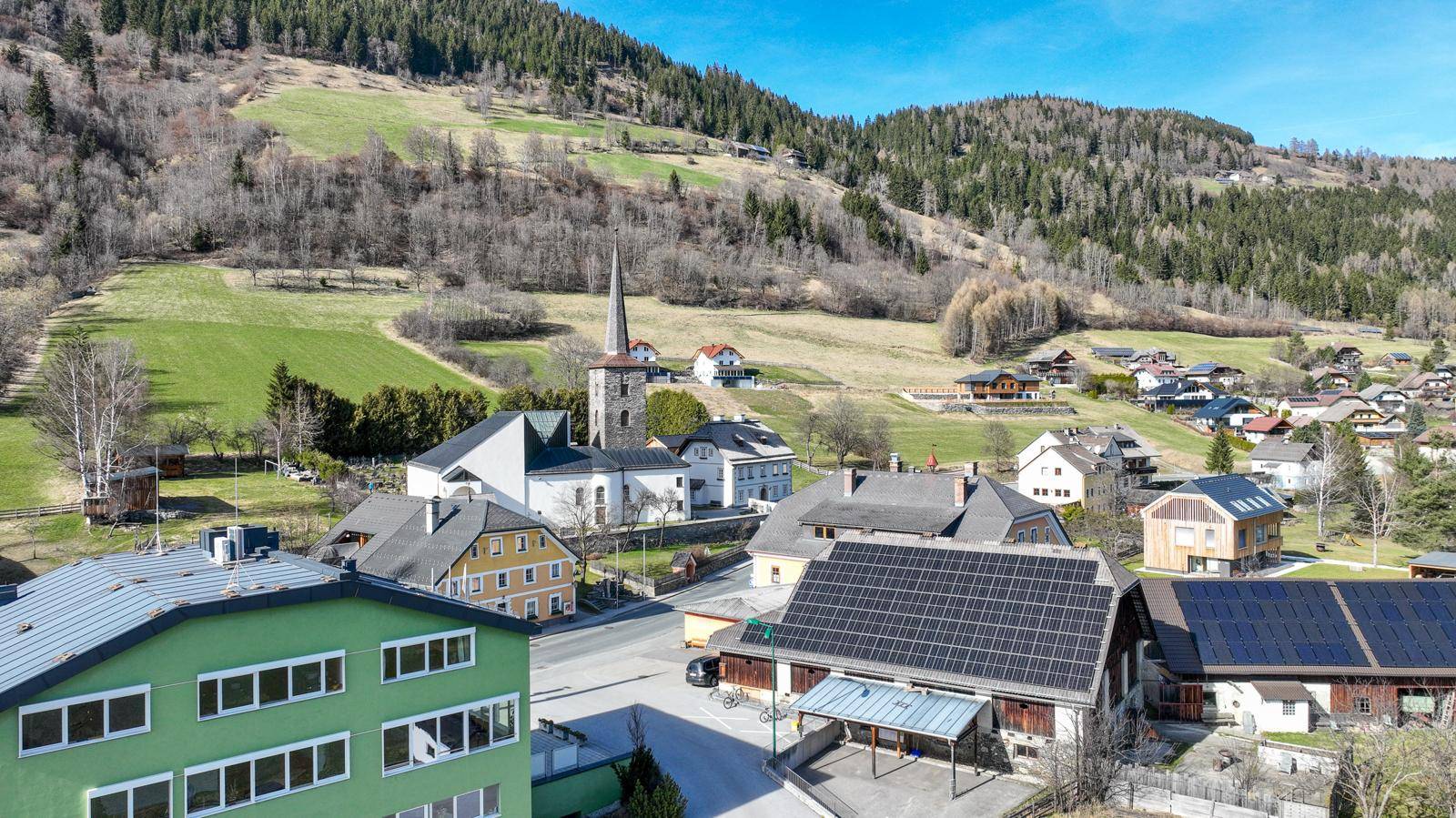 Panoramablick auf ein ländliches Dorf mit Kirche und grünen Hügeln.