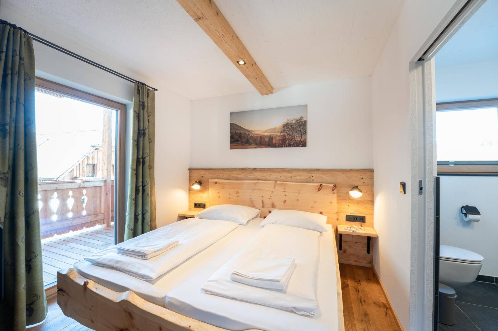 Gemütliches Schlafzimmer mit Holzbett, Balkonzugang und Blick auf die Umgebung.