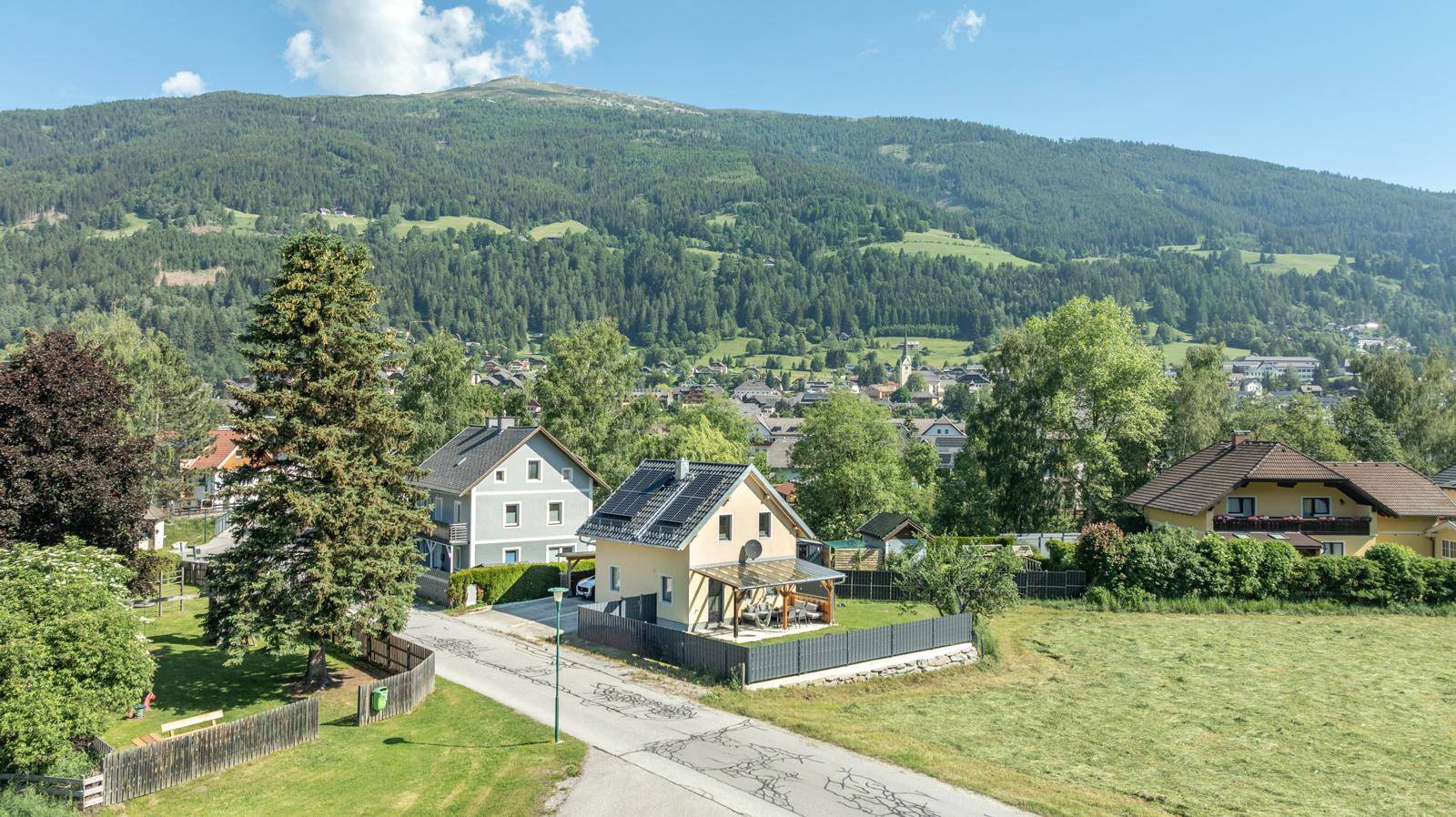 Weitläufige Ansicht des Hauses mit Photovoltaikanlage, umgeben von Natur und Bergen.