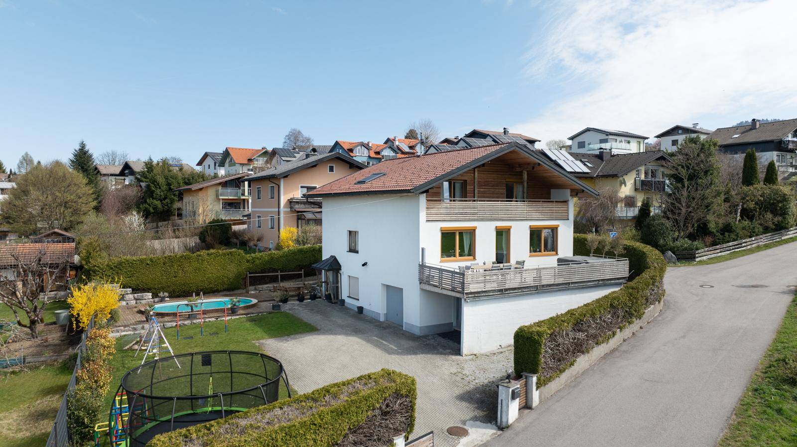 Luftaufnahme eines Einfamilienhauses mit Garten, Pool, Trampolin und Spielplatz in ländlicher Umgebung.