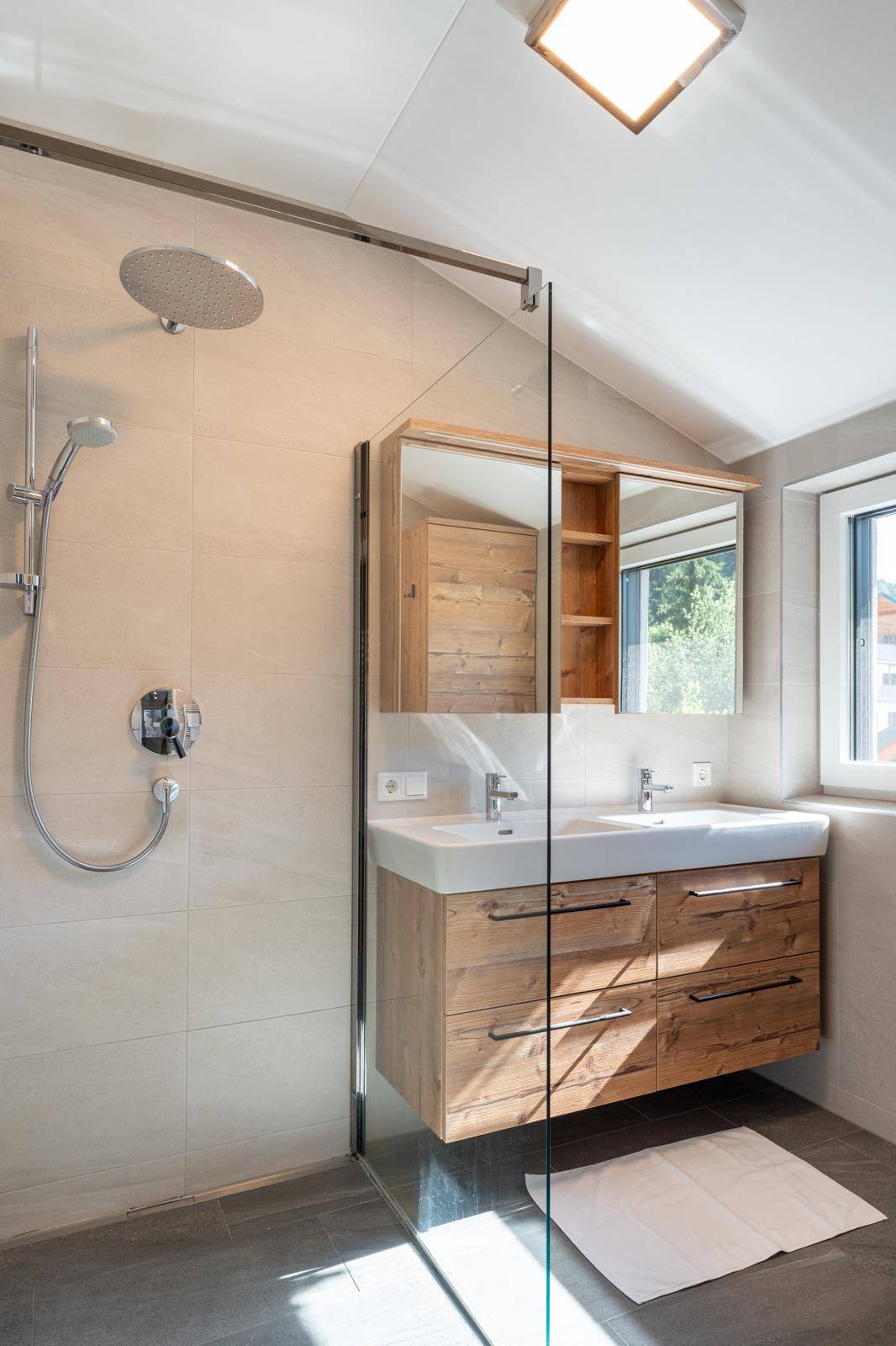 Modernes Badezimmer mit Doppelwaschbecken, begehbarer Dusche und Fenster.