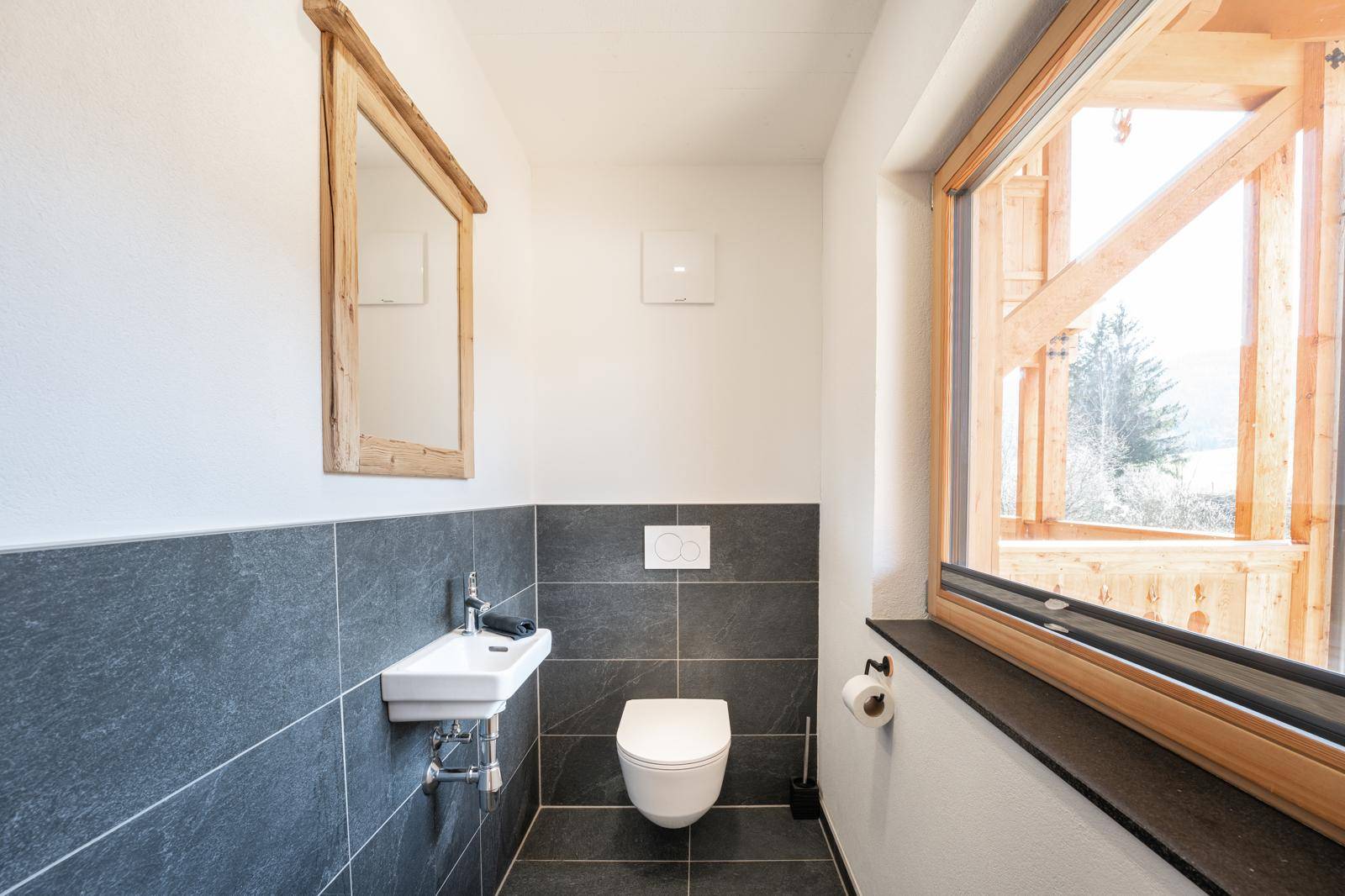Modernes Gäste-WC mit kleinem Waschbecken, Wand-WC und Fenster mit Ausblick.