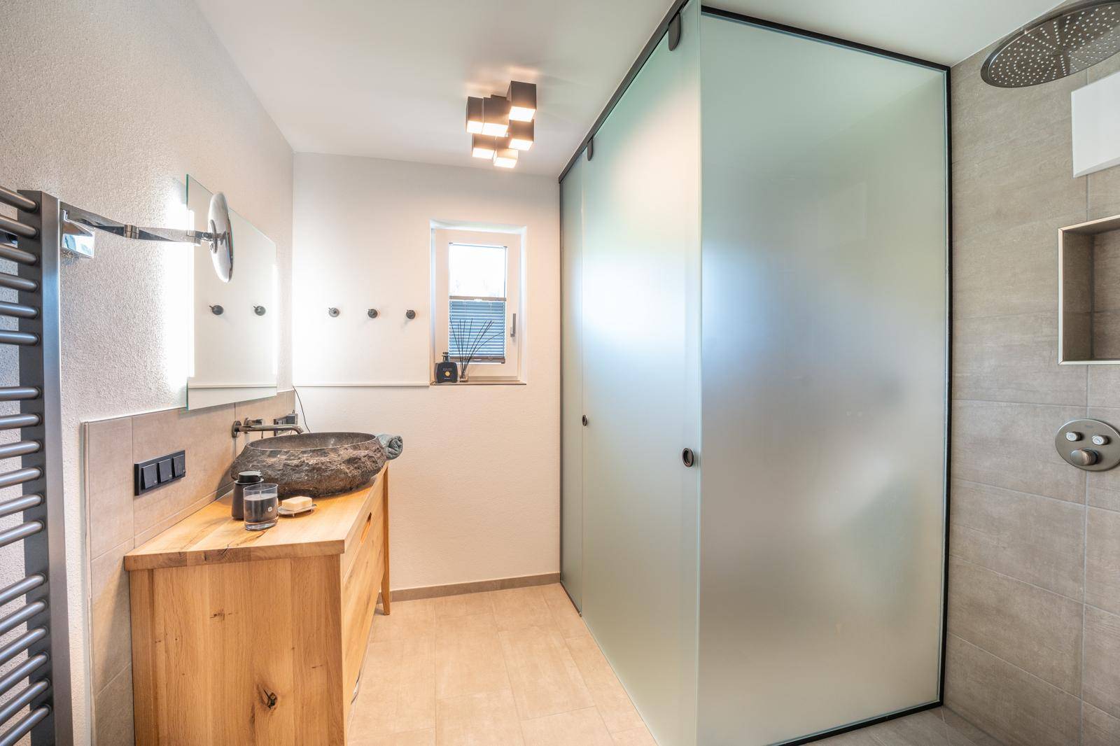 Modernes Badezimmer mit begehbarer Dusche, Natursteinwaschbecken und Fenster.