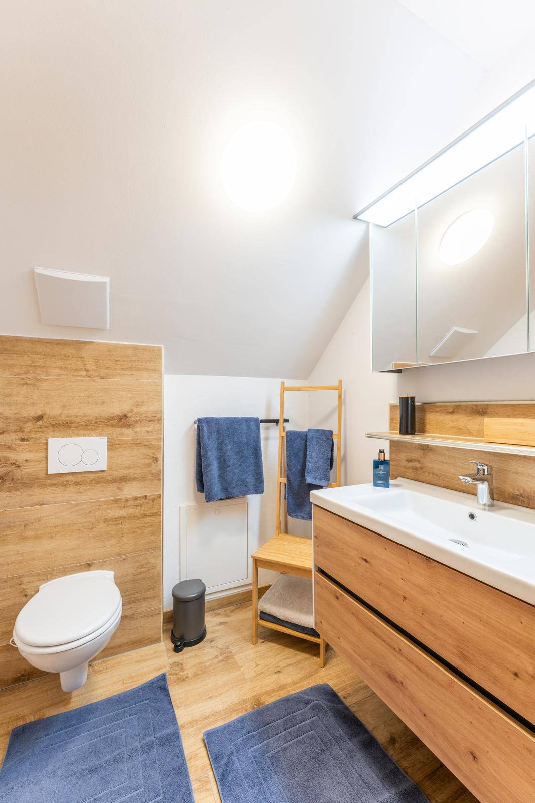 Helles Badezimmer im Dachgeschoss mit WC, Waschbecken und Holzdetails.