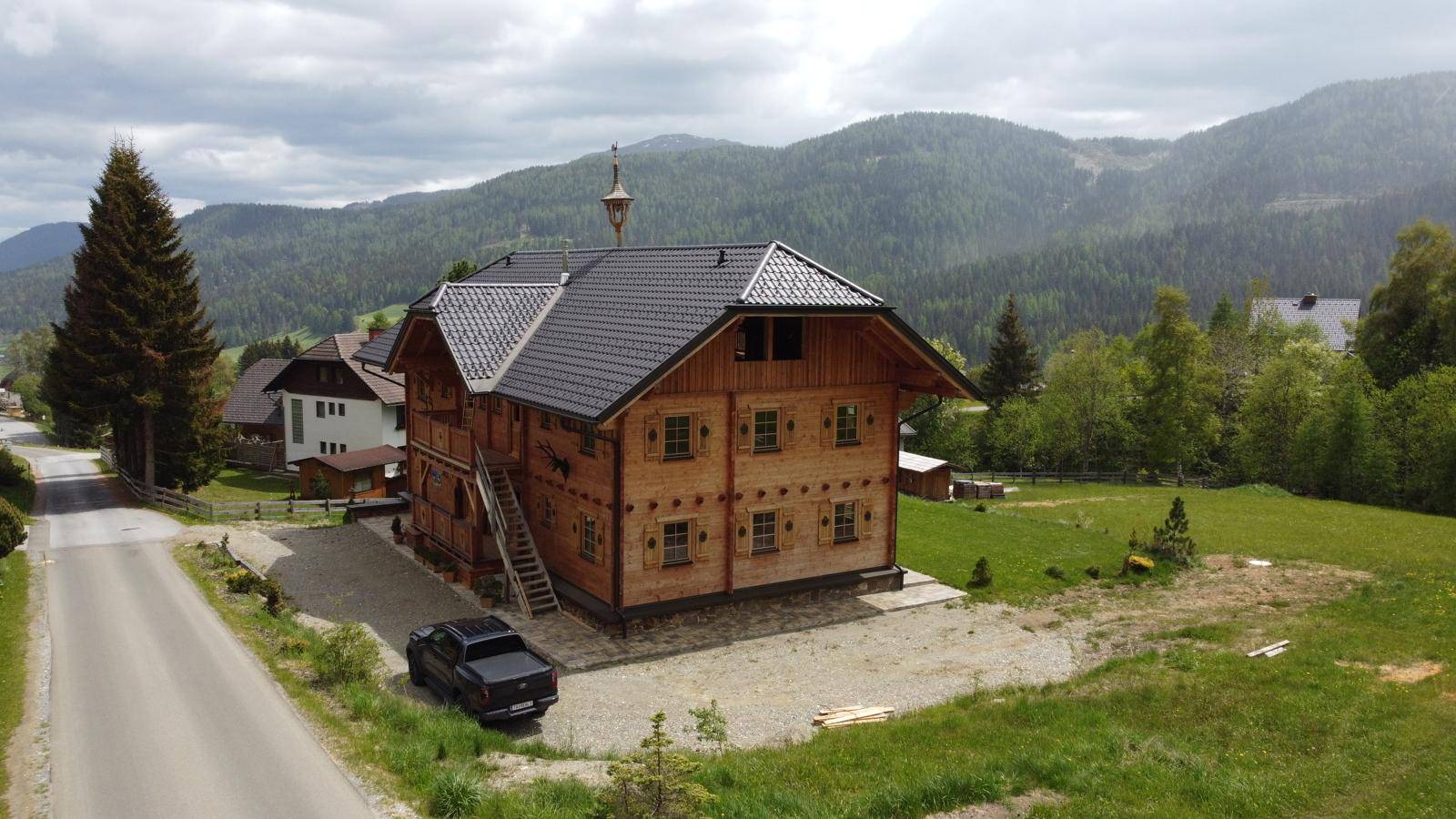 Neubau-Chalet in den Bergen mit weitem Blick über die Landschaft und eine Landstraße.