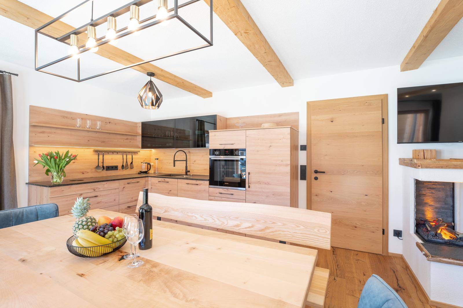 Moderne Holzküche mit integrierten Geräten, Esstisch und Blick auf den Kamin.