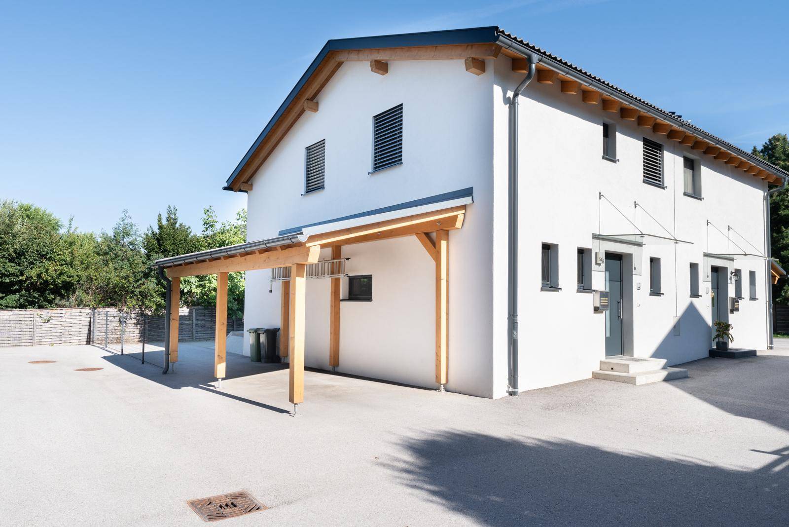 Seitenansicht des modernen Hauses mit Carport und gepflegter Außenanlage.