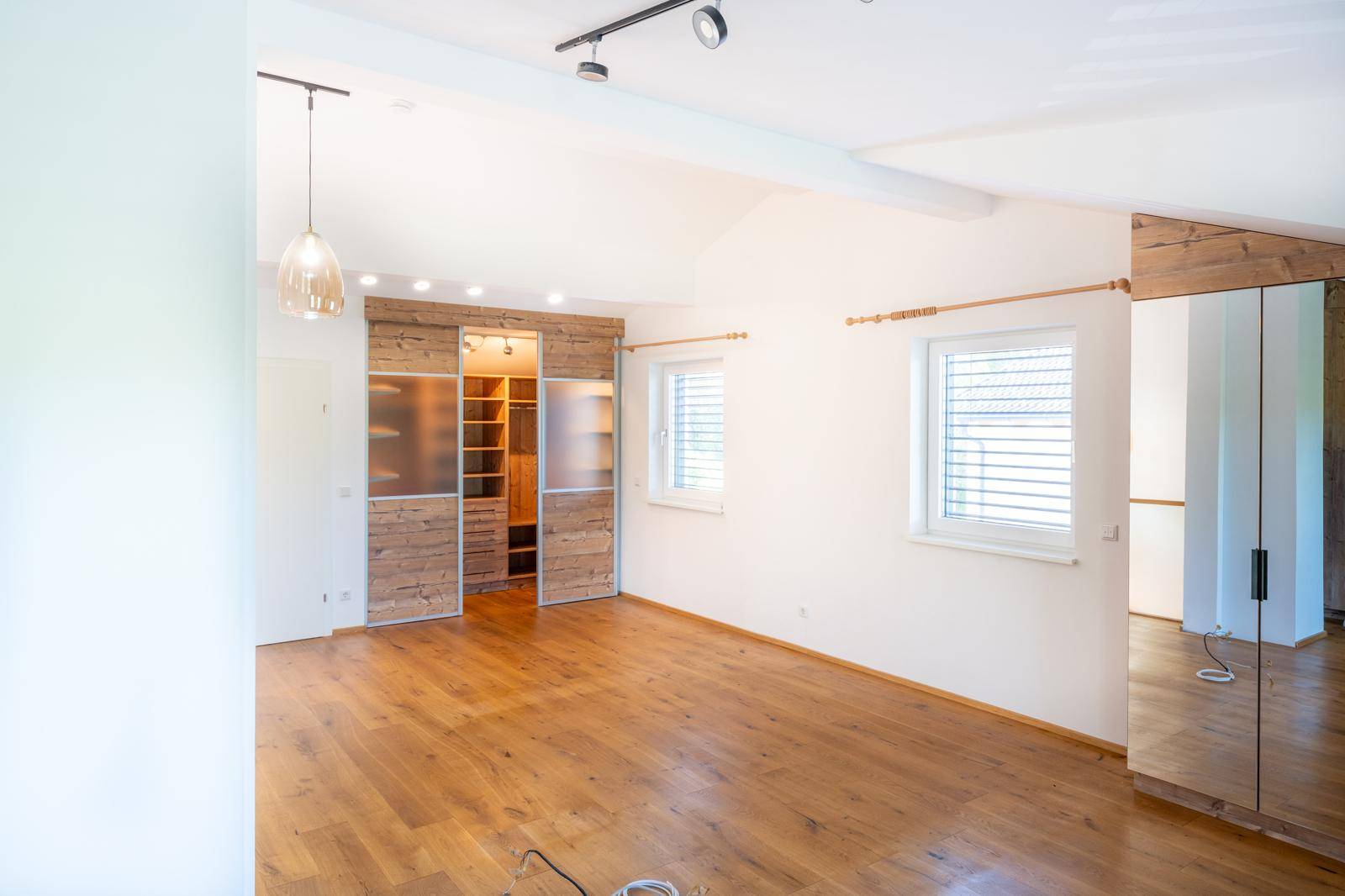 Geräumiges Schlafzimmer mit Holzboden, Einbauschränken und viel Tageslicht.