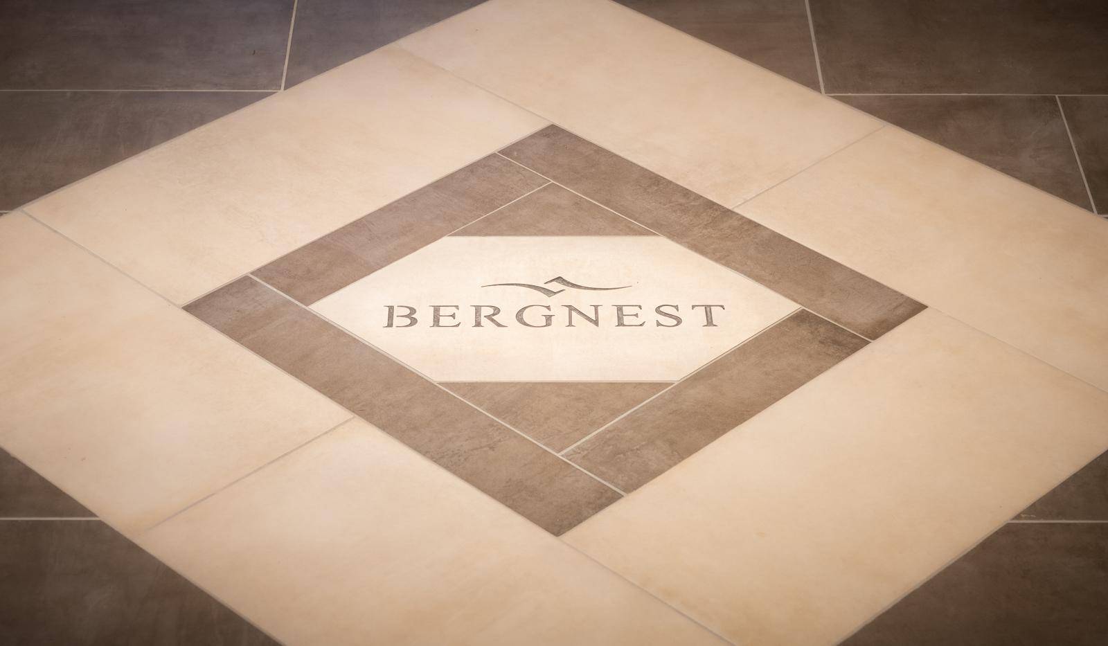 Detailaufnahme eines Fliesenbodens mit einem dekorativen Logo in der Mitte.