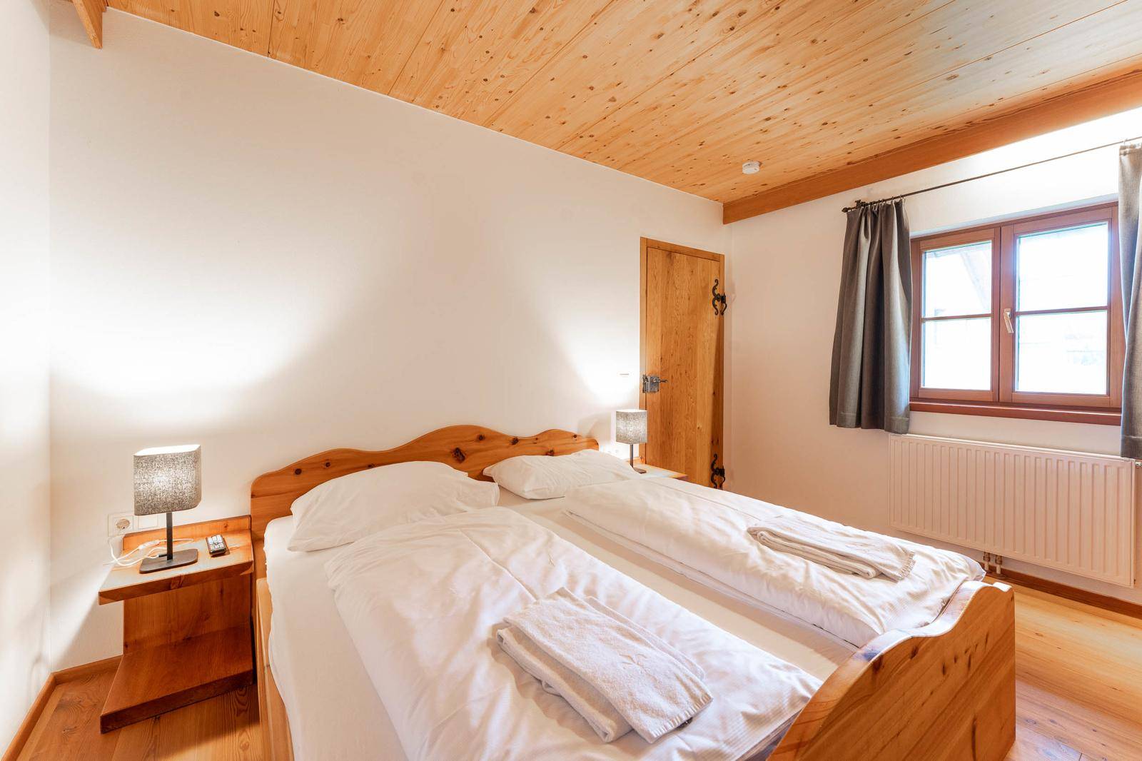 Gemütliches Schlafzimmer mit Doppelbett, Holzboden und natürlichem Lichteinfall.