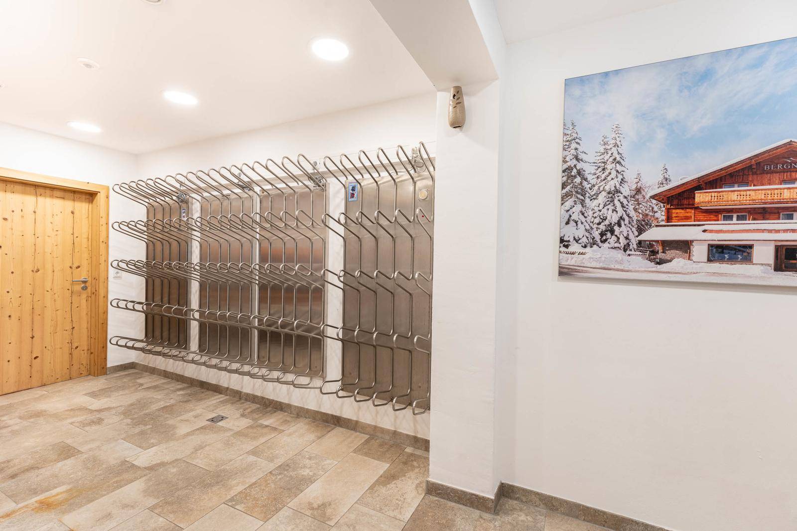 Praktischer Skiraum mit Wandhalterungen für Skier und Stiefel sowie einem großen Wandbild.