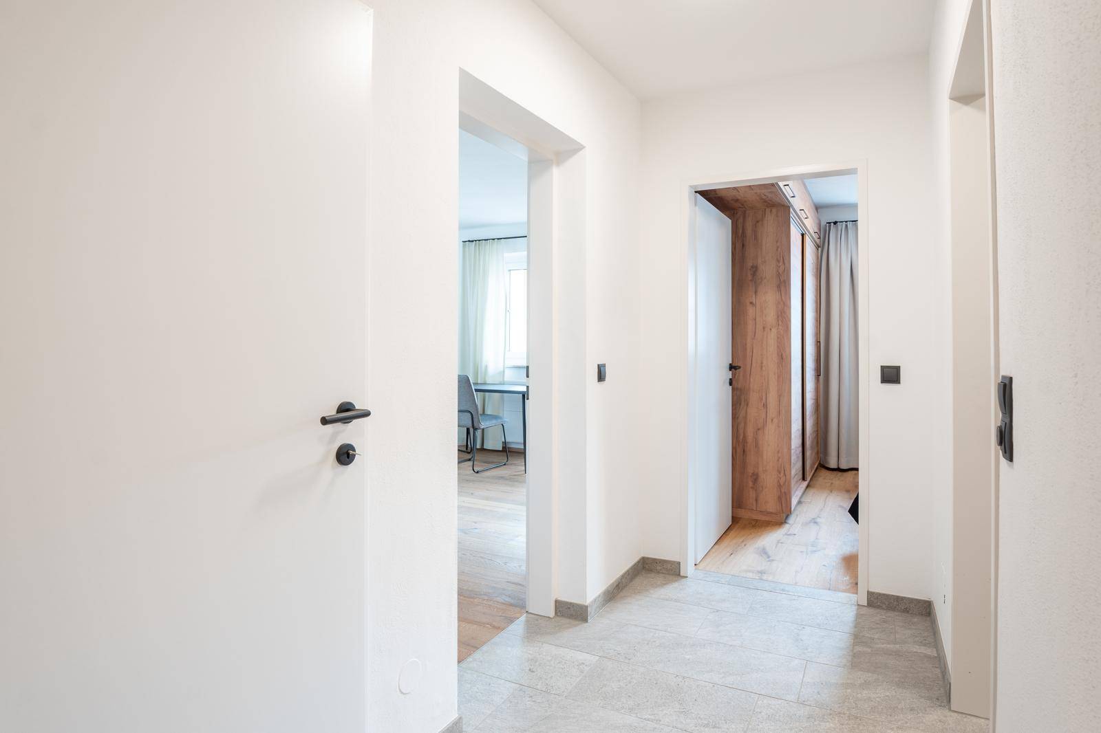 Heller Flur mit Fliesenboden und Zugang zu verschiedenen Zimmern der Wohnung.