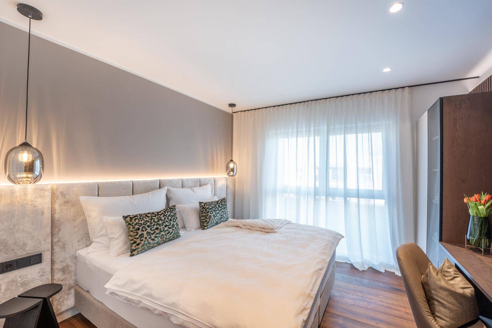 Gemütliches Schlafzimmer mit großem Bett, indirekter Beleuchtung und Vorhängen.