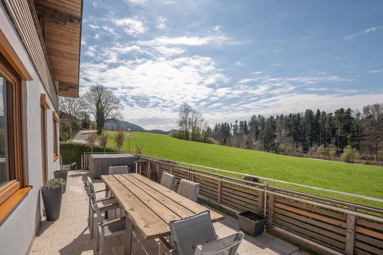 Geräumige Terrasse mit großem Holztisch und Stühlen, ideal für Mahlzeiten im Freien mit Blick auf die Natur.