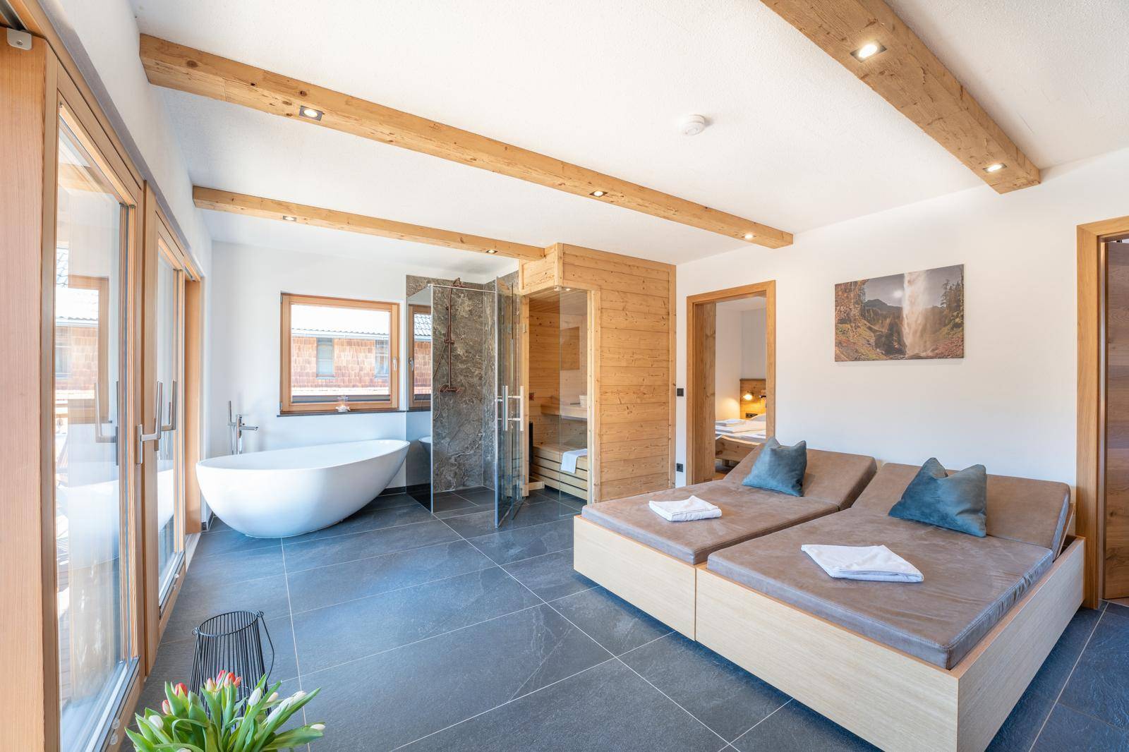 Luxuriöser Wellnessbereich mit freistehender Badewanne, Sauna und Liegeflächen.