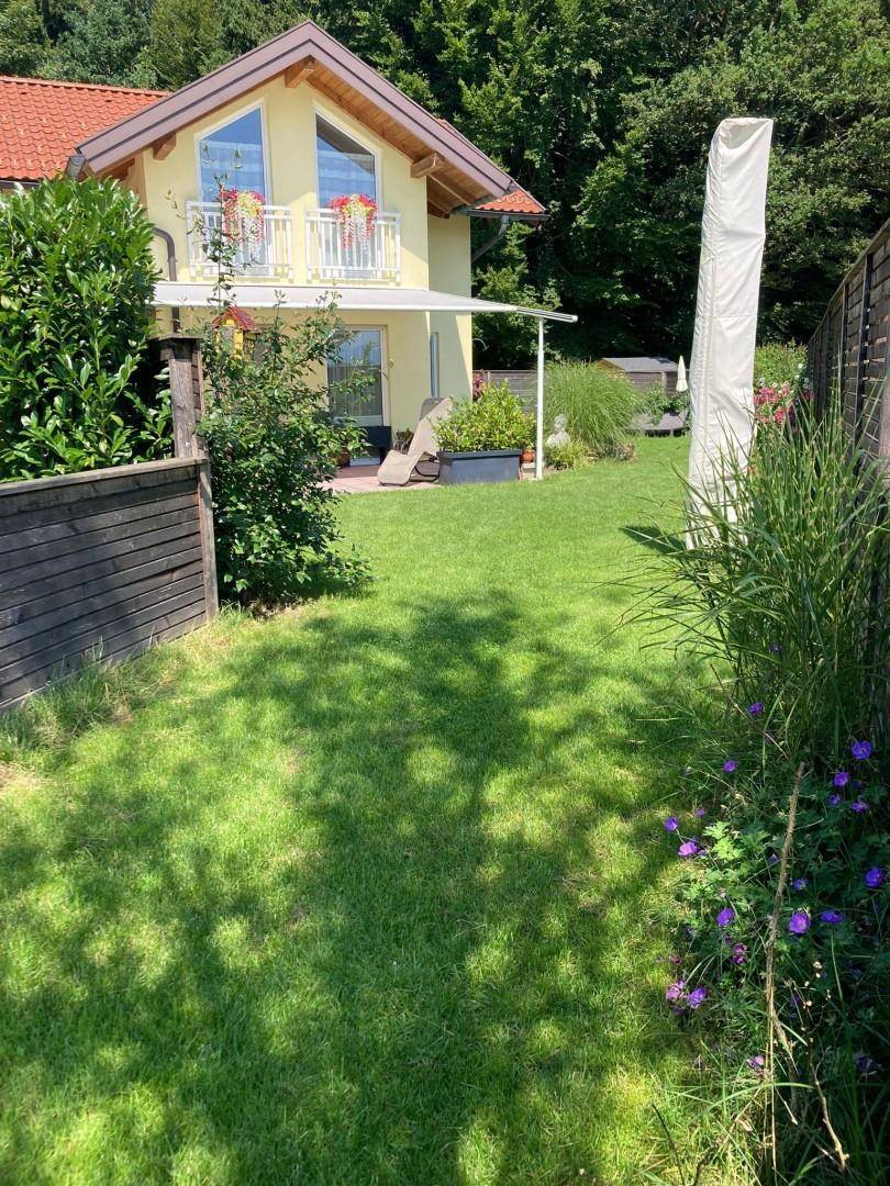 Charmantes Haus mit gepflegtem Garten, Rasenfläche und üppiger Bepflanzung.