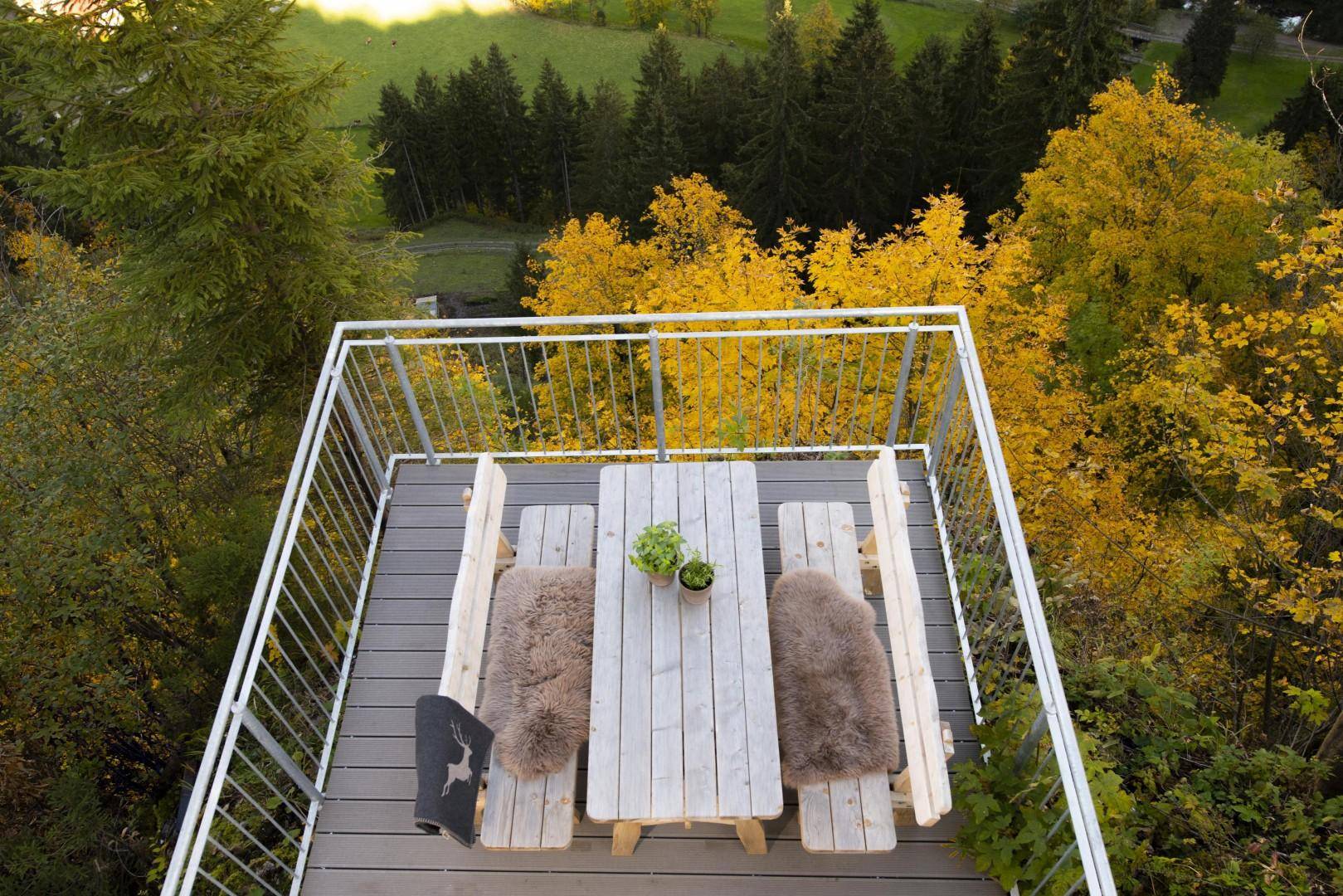 Gemütlicher Essbereich im Freien auf einer erhöhten Terrasse mit Blick ins Grüne.