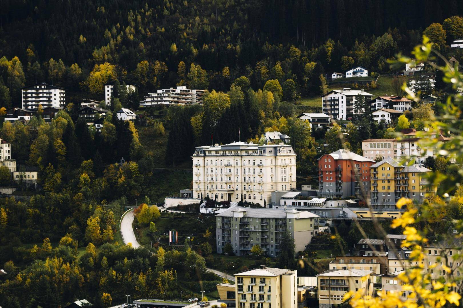 Malerische Ansicht einer Bergstadt, umgeben von Wäldern und alpiner Landschaft.