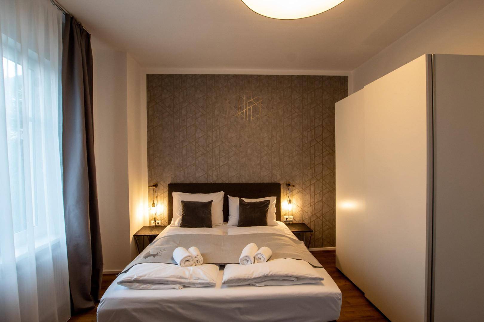 Gemütliches Schlafzimmer mit Doppelbett, dekorativer Akzentwand und weißem Kleiderschrank.