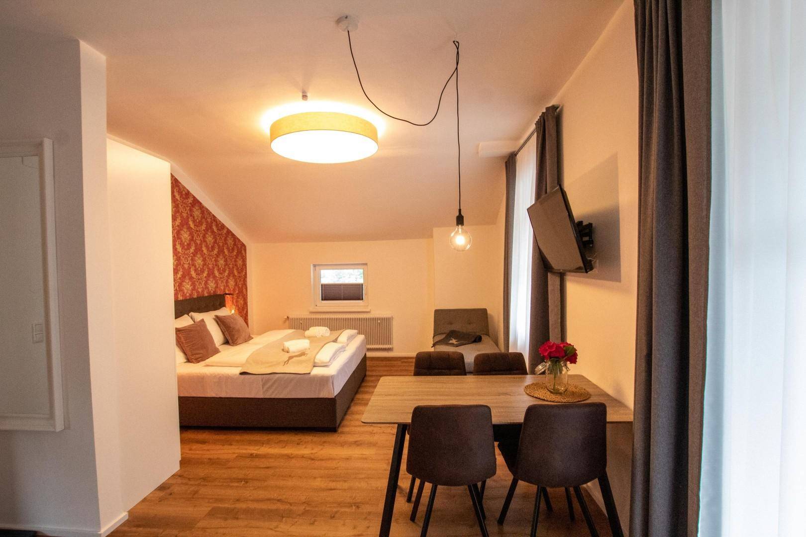 Kombinierter Wohn- und Schlafbereich mit Doppelbett, Esstisch und Fernseher.