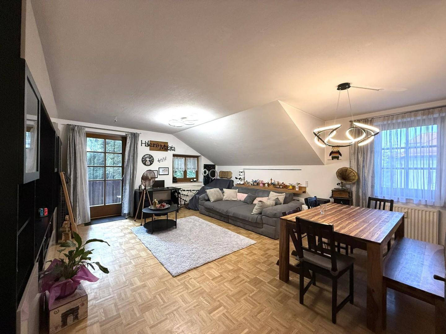 Heller Wohn- und Essbereich im Dachgeschoss mit Holzboden und Zugang zum Balkon.