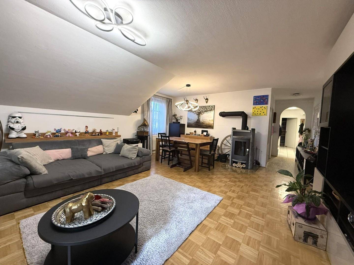 Geräumiger Wohn- und Essbereich mit Kaminofen, Holzboden und moderner Einrichtung.