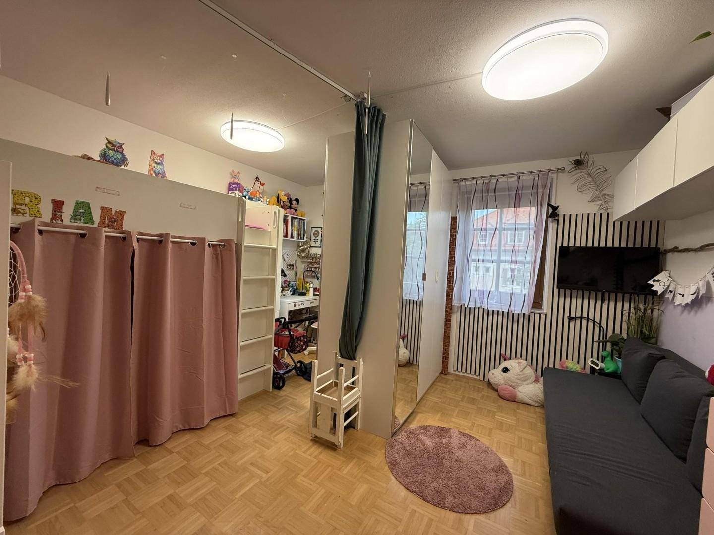 Helles Kinderzimmer mit Hochbett, Schrank und Sofa, ideal für junge Bewohner.