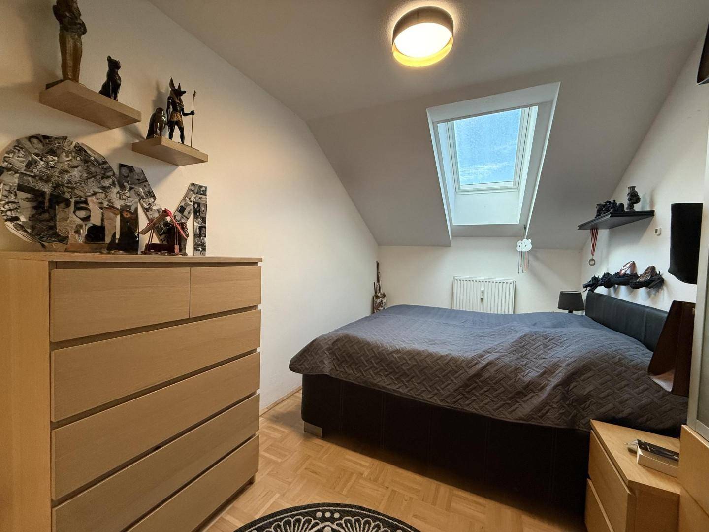Gemütliches Schlafzimmer im Dachgeschoss mit Holzboden und Dachfenster.