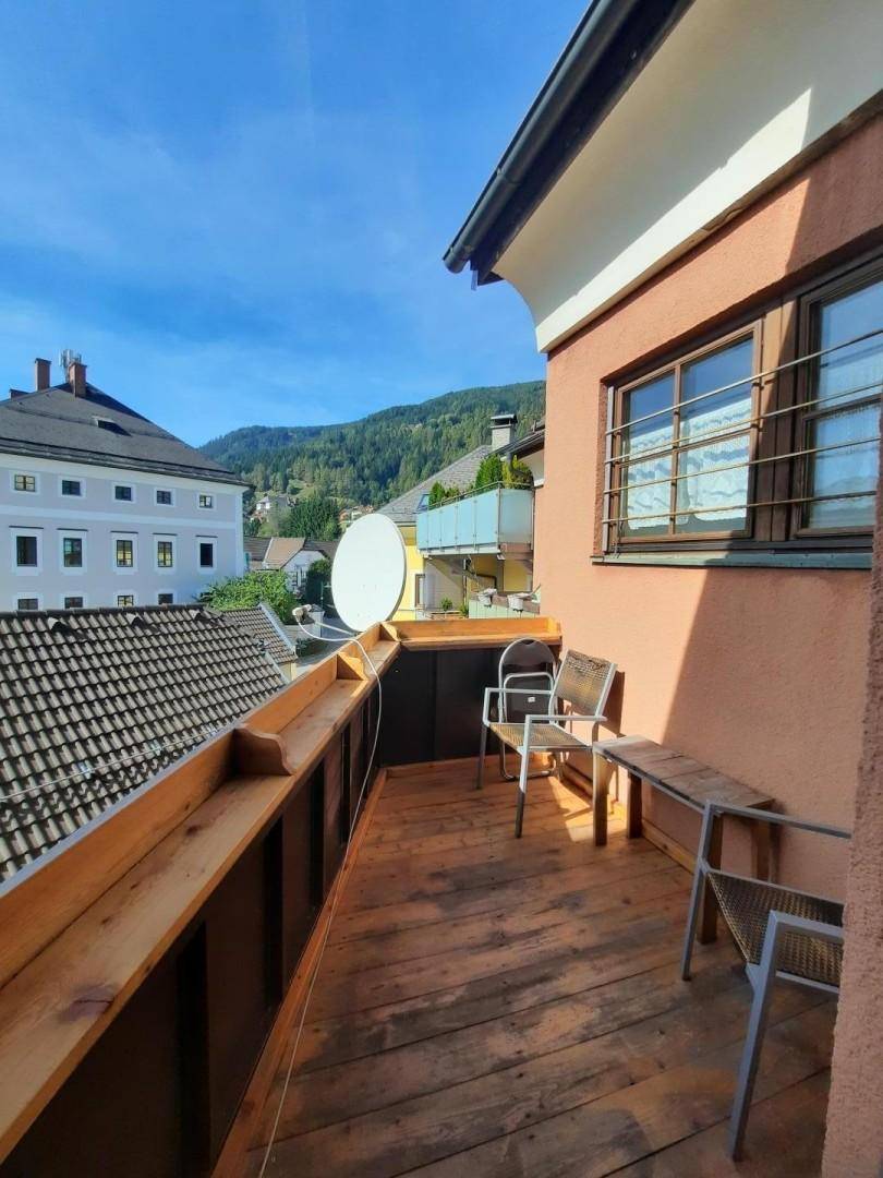 Sonnenverwöhnter Balkon mit Holzboden, Sitzgelegenheiten und einem weiten Blick auf die Berge.