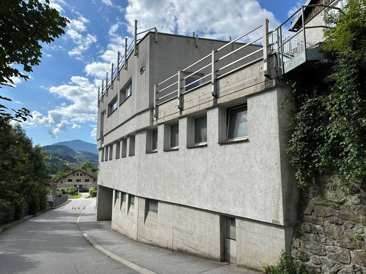 Ansicht des Gebäudes von der Seite mit Balkon und Blick auf die umliegende Landschaft.