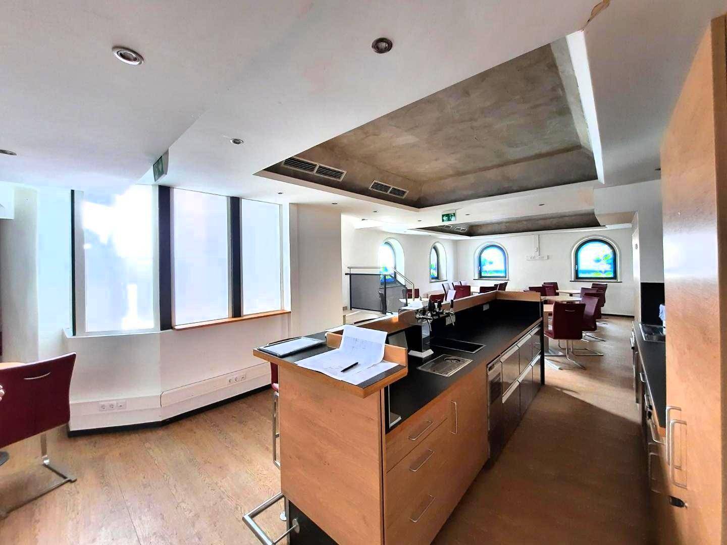 Moderne Theke mit Spülbecken und Arbeitsfläche, umgeben von Sitzgelegenheiten und großen Fenstern.