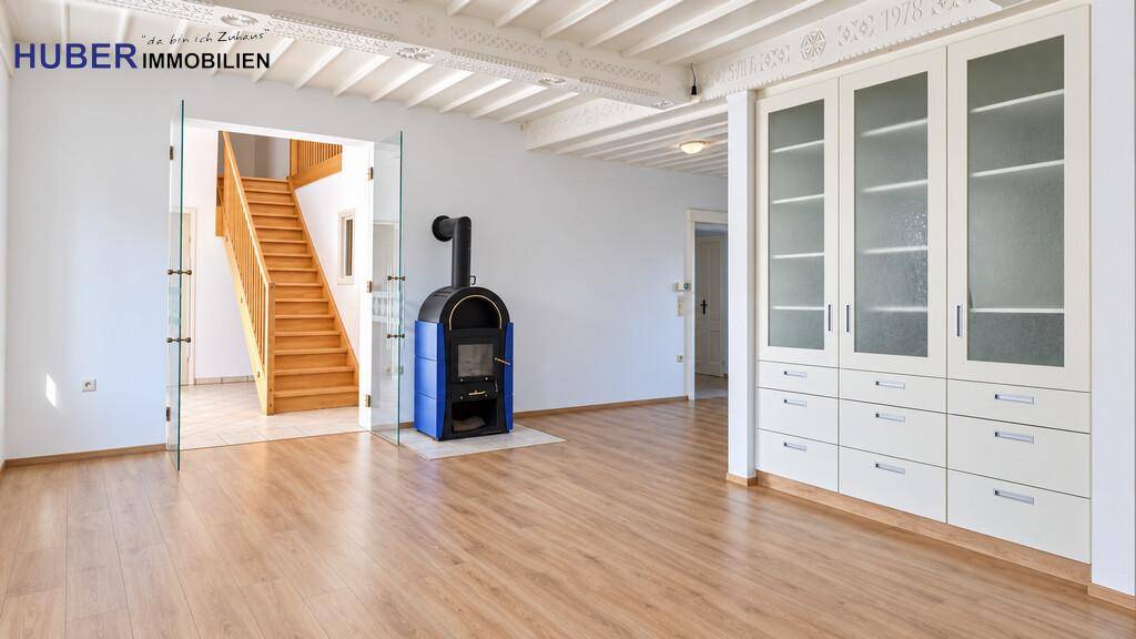 Heller Wohnbereich mit Holzofen, Einbauschrank und Treppe zum Obergeschoss.