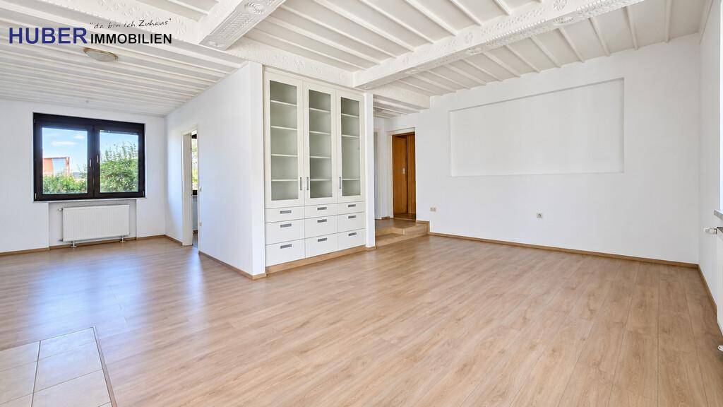 Helles Wohnzimmer mit Holzbalkendecke, Einbauschrank und hellem Laminatboden.