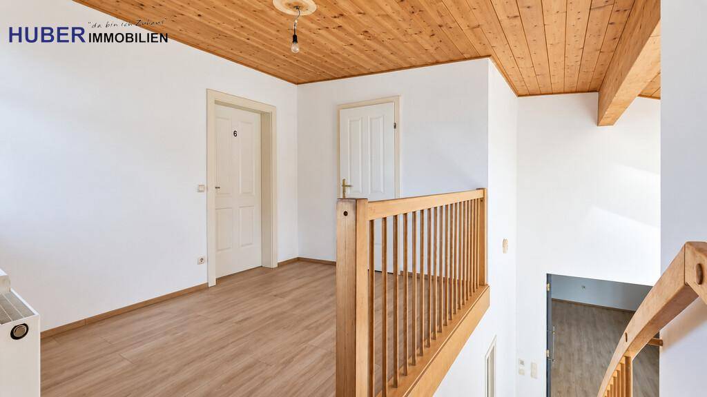 Obergeschoss-Flur mit Holzdecke, Laminatboden und Zugang zu mehreren Zimmern.