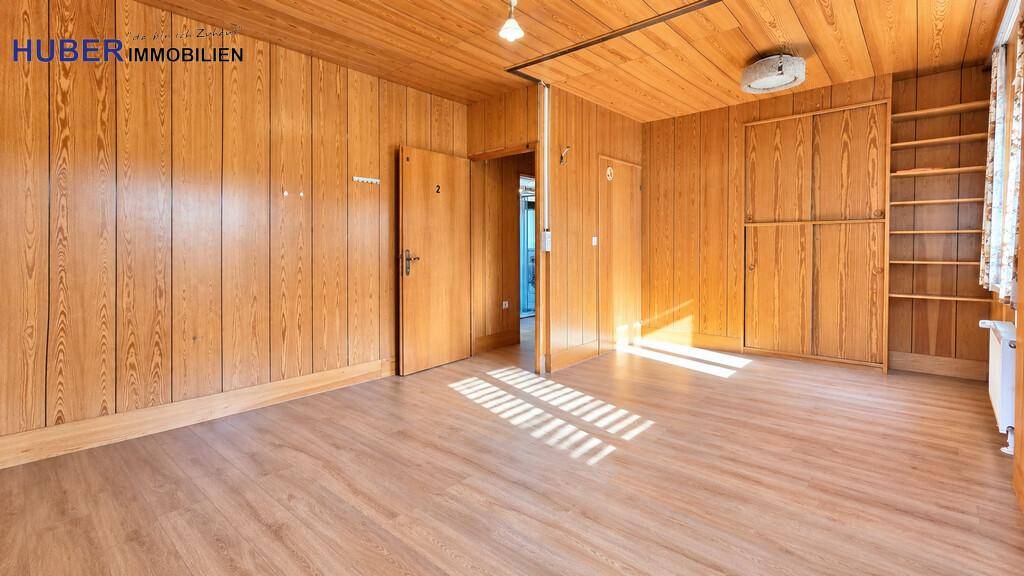 Geräumiger Wohnbereich mit durchgehender Holzvertäfelung und integrierten Regalen.