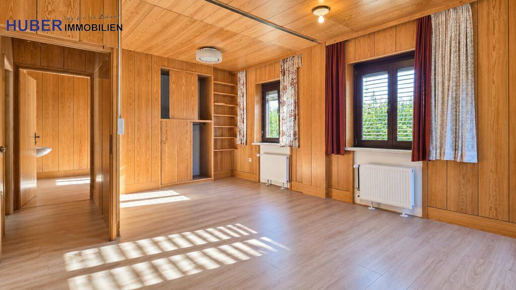 Gemütlicher Wohnraum mit Holzvertäfelung an Wänden und Decke sowie Laminatboden.