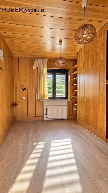 Kleineres Zimmer mit Holzvertäfelung, Fenster und zwei dekorativen Hängelampen.