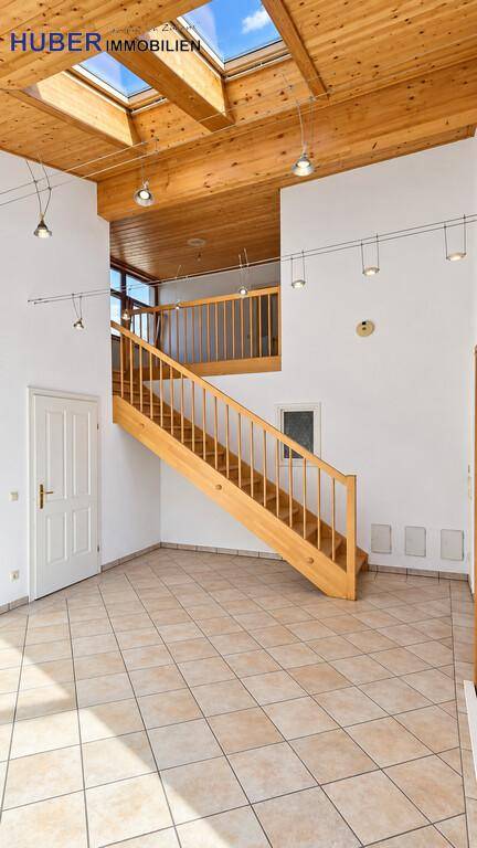 Geräumiger Eingangsbereich mit Holztreppe, Fliesenboden und Zugang zum Wintergarten.